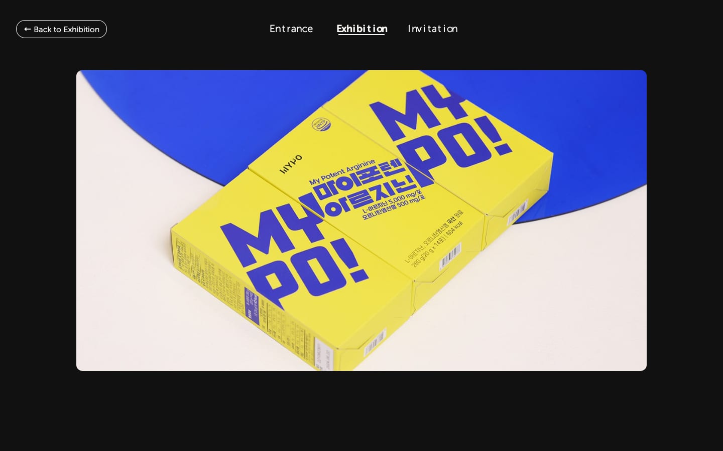 A project detail page: a full-width photograph of yellow supplement packaging on a blue and cream ground, under a Back to Exhibition button and the site navigation