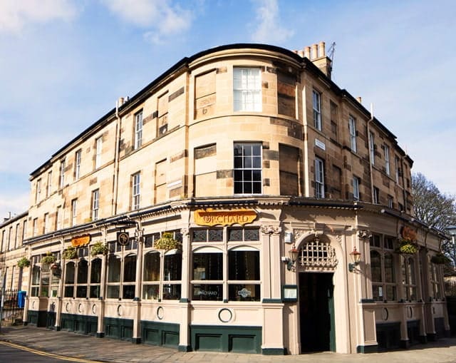 The Orchard Bar on its corner site in Canonmills, Edinburgh: a sandstone tenement building with green and cream painted frontage and a gold ORCHARD sign above the door